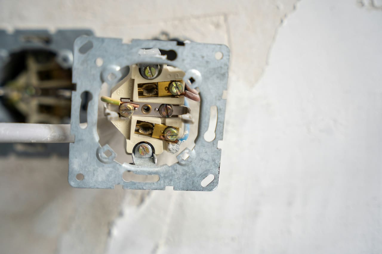 Electrical outlet opened up to show the wiring behind it
